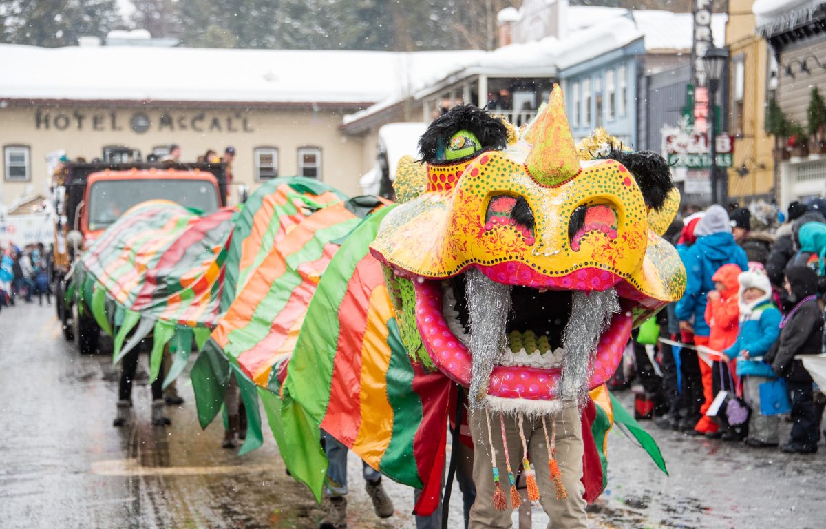 A colorful Chinese dragon dances through a snowy parade.