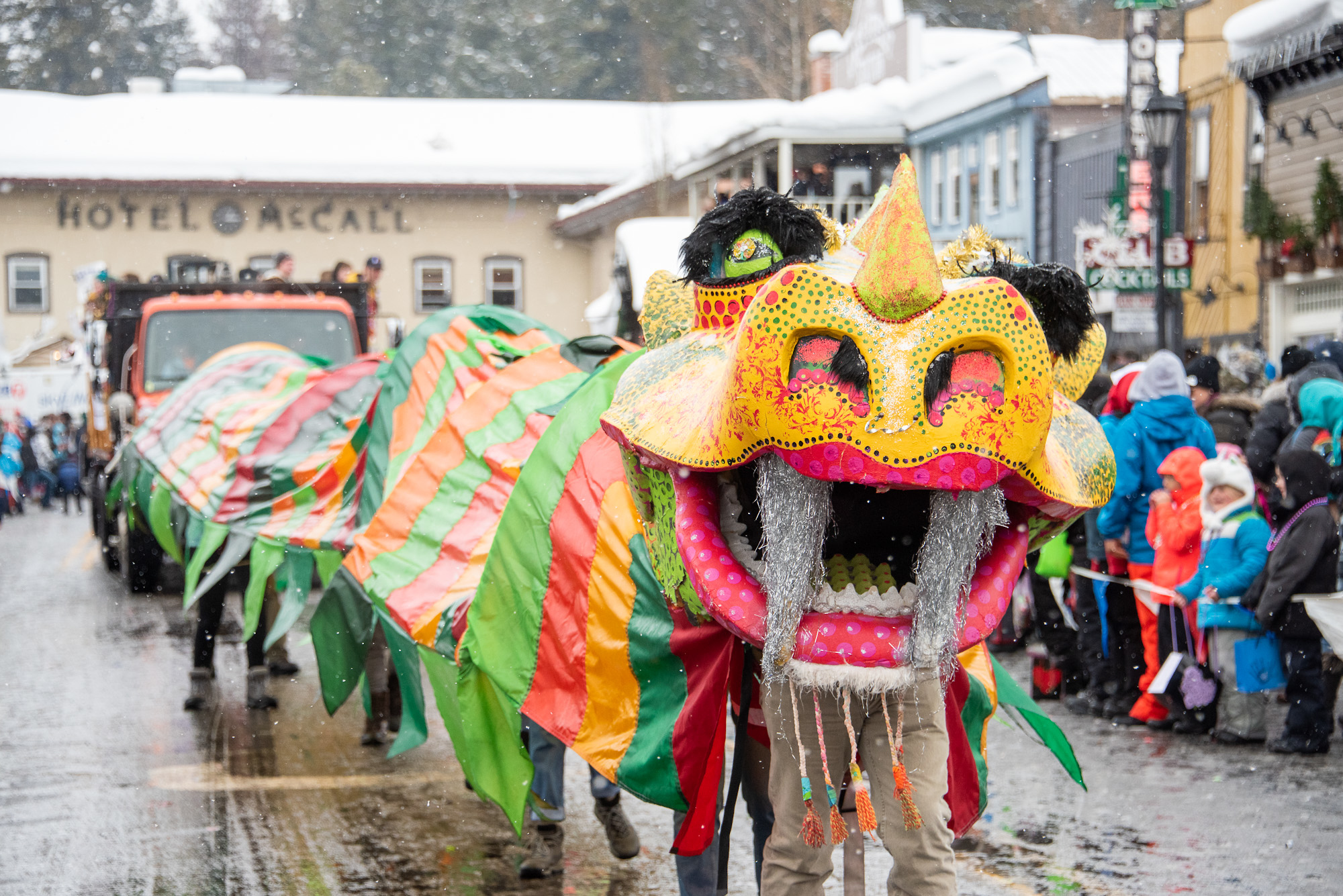A colorful Chinese dragon dances through a snowy parade.