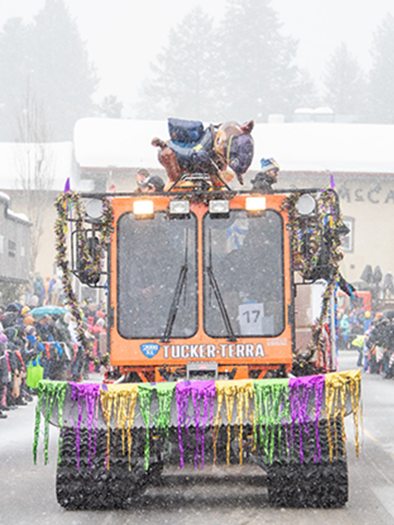 An orange truck decorated with lights and streamers in the snow.