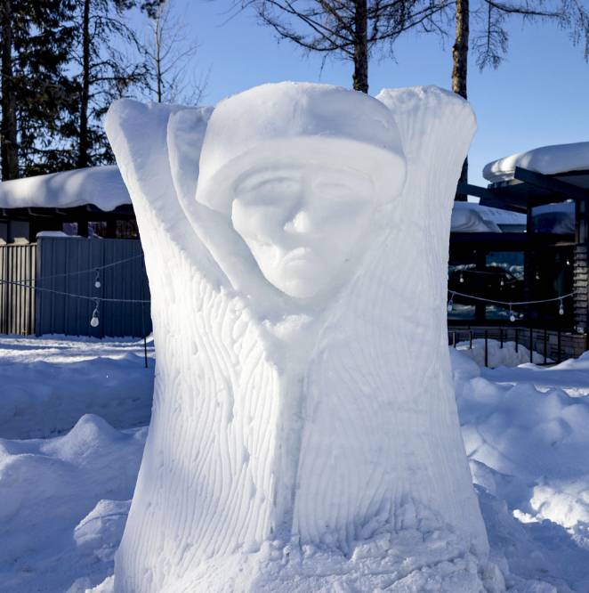 A person in a coat sculpted out of ice and snow.