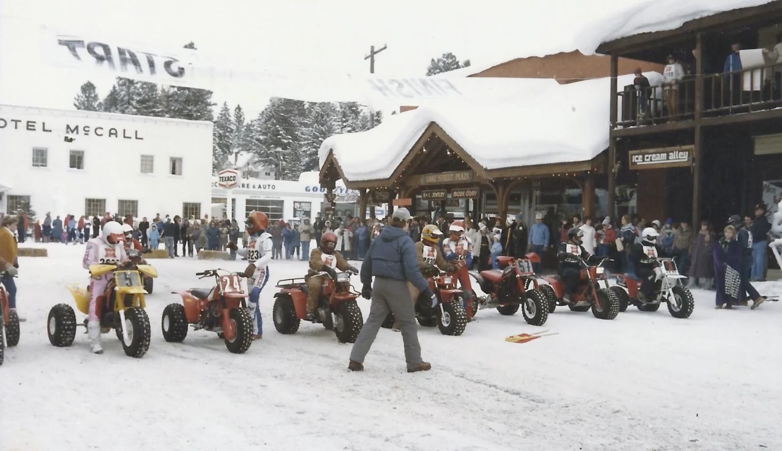 People line up on three-wheeler ATVs for a race in the snow.