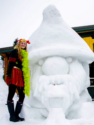 A woman poses with a gnome ice sculpture.