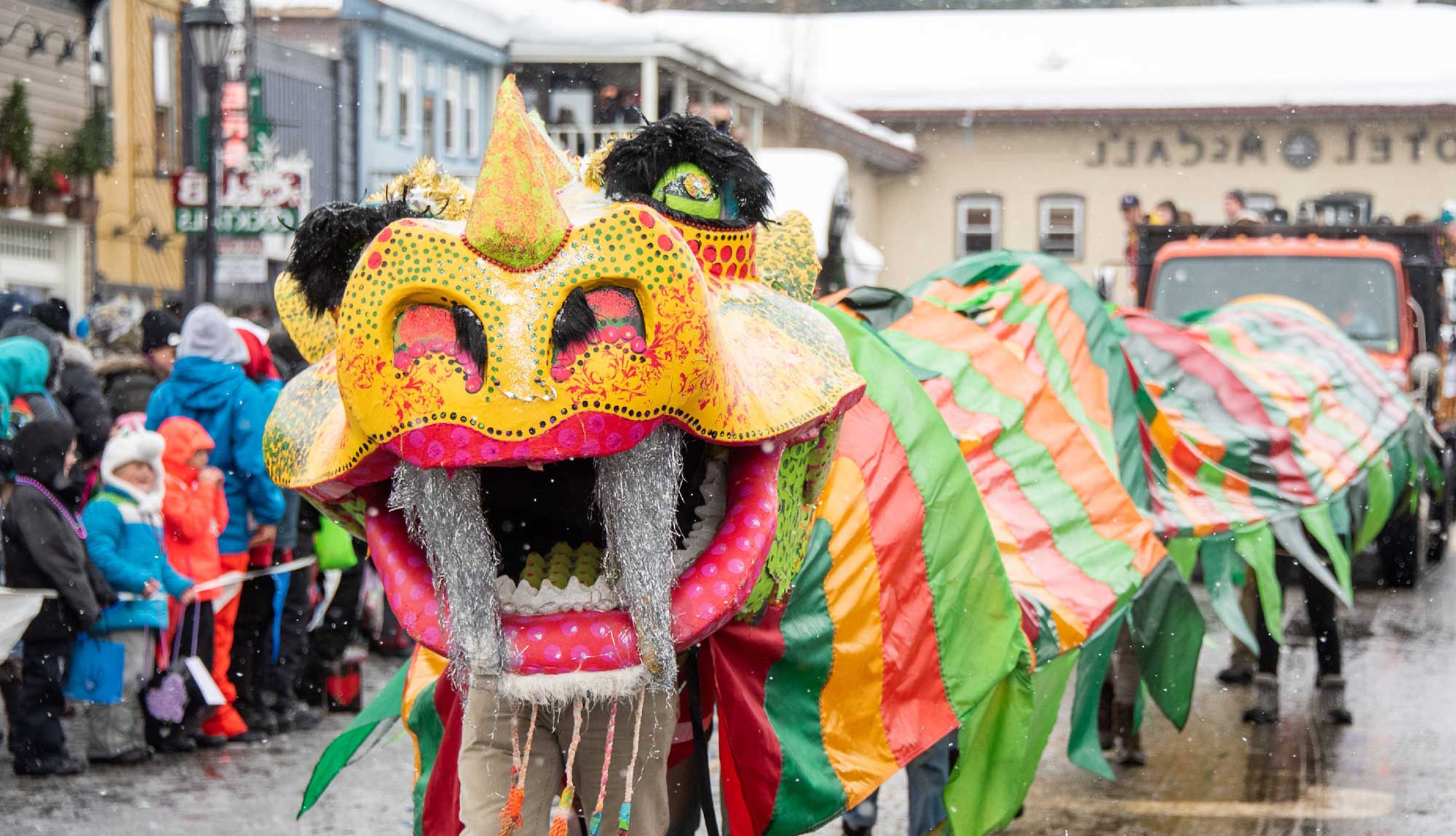 A colorful Chinese dragon dances through a snowy parade.