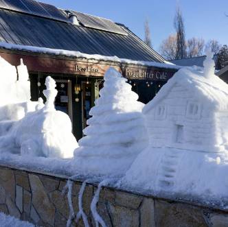 A train, tree, and cottage sculpted out of ice and snow.