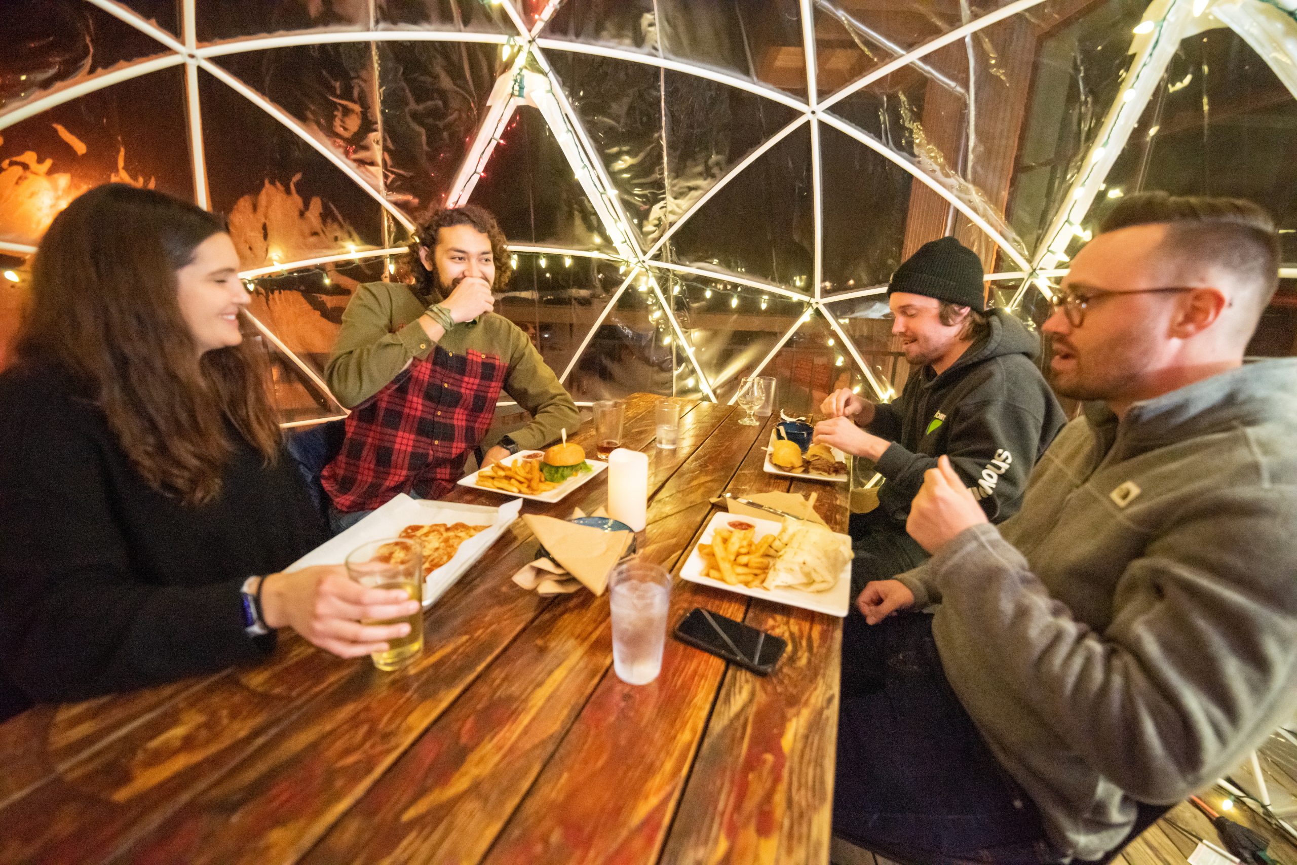 A group of four people seated around a table enjoying a meal at Salmon River Brewery.