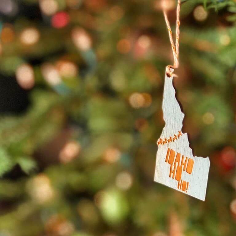A wooden Idaho ornament hanging from a Christmas tree.