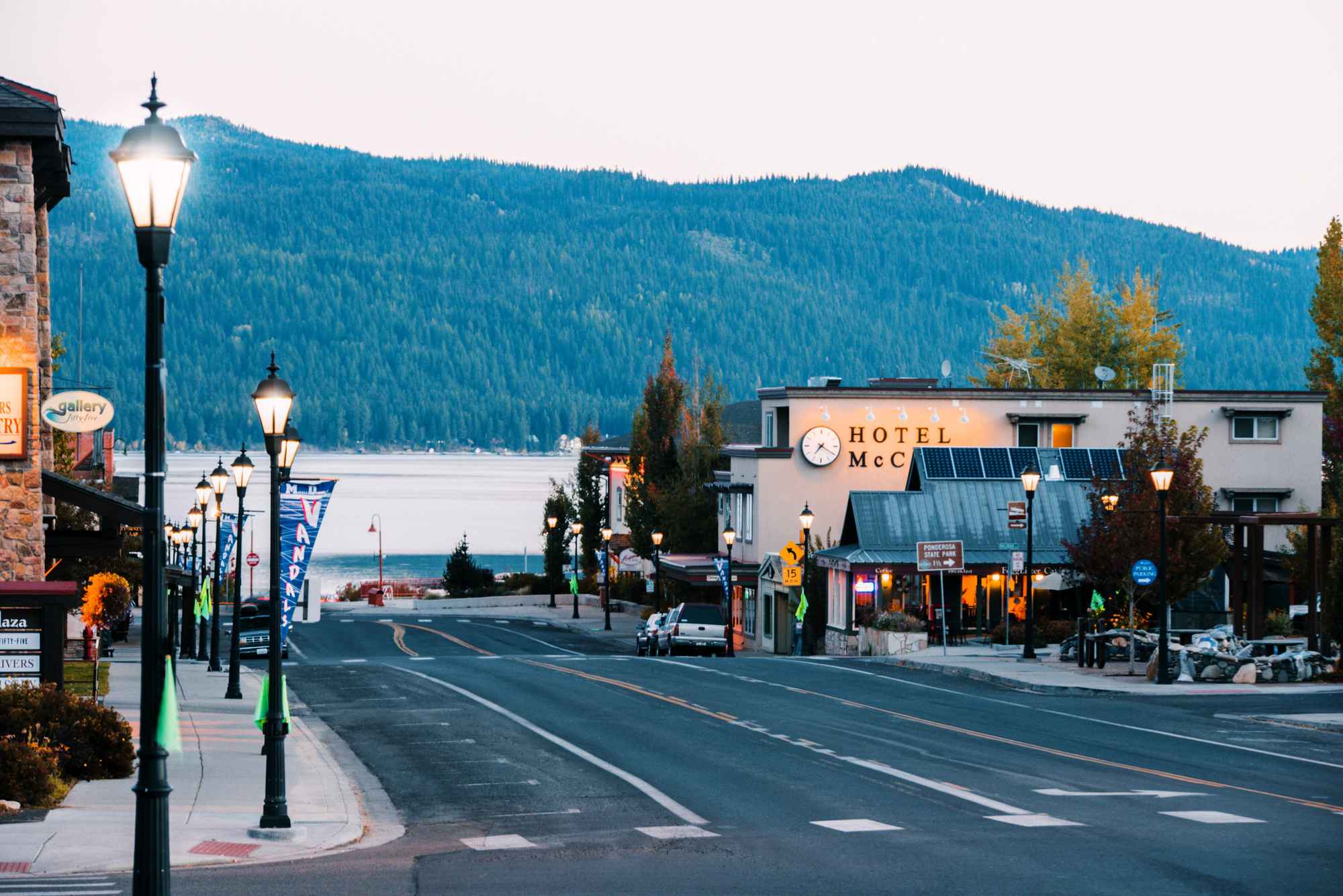 A view of a street lined with buildings in downtown McCall, and in the background, Lake Payette backed by a forest.