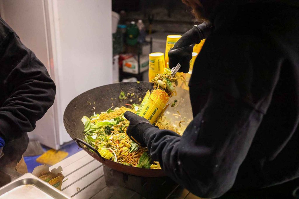 Person serving food from a wok at the McCall Winter Carnival.